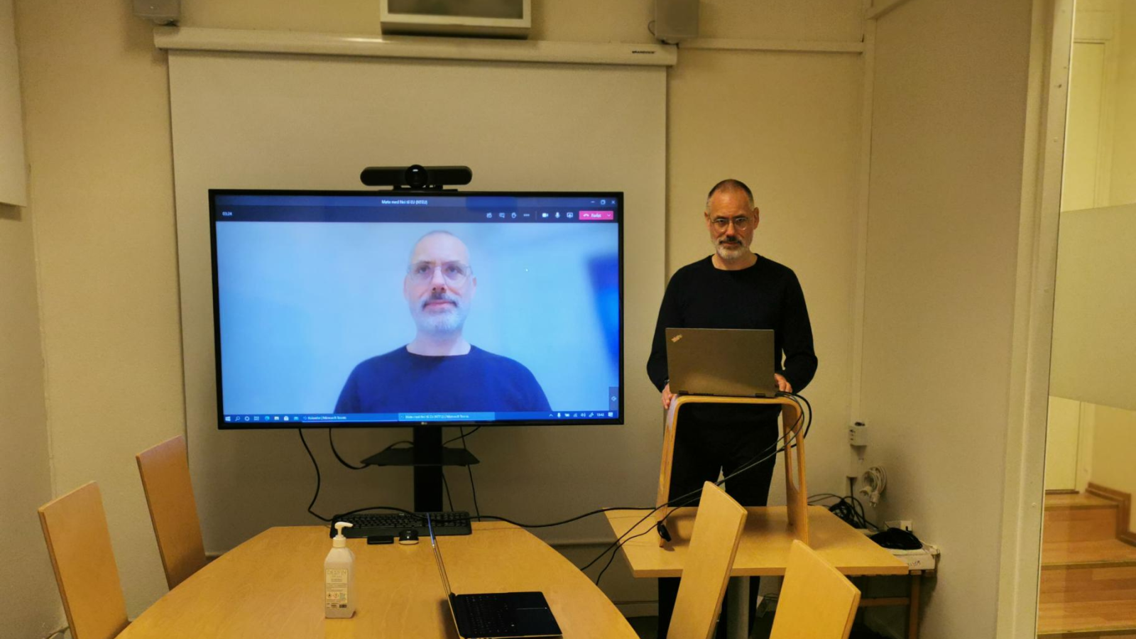 Mulig oppsett av delegasjonens møterom. Laptopen på den provisoriske talerstolen er koblet til skjermen. Den innebygde mikrofonen og kameraet på laptopen viser taleren. Lyden fra møtet går via høyttalerne på TV-en.  